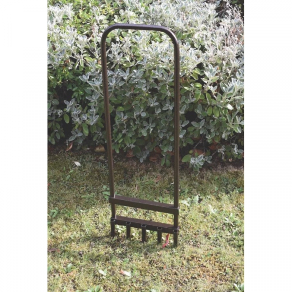 Ručný dutinkový aerifikátor Spear & Jackson voľne stojaci na trávniku pred okrasnou výsadbou v záhrade od stonetrade.