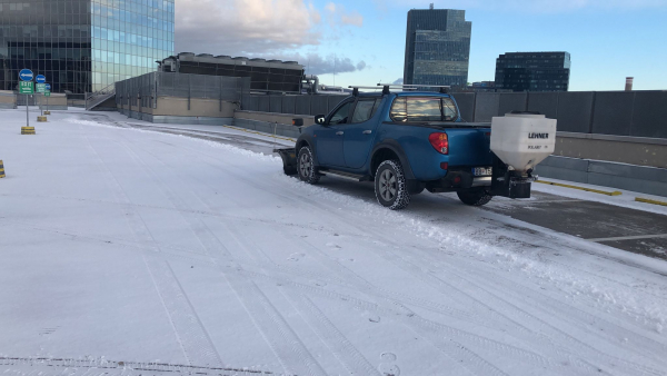 Vozidlo Mitsubishi L200 spoločnosti STONE TRADE vybavené prednou radlicou a profesionálnym sypačom LEHNER POLARO 170 počas zimnej údržby parkoviska.