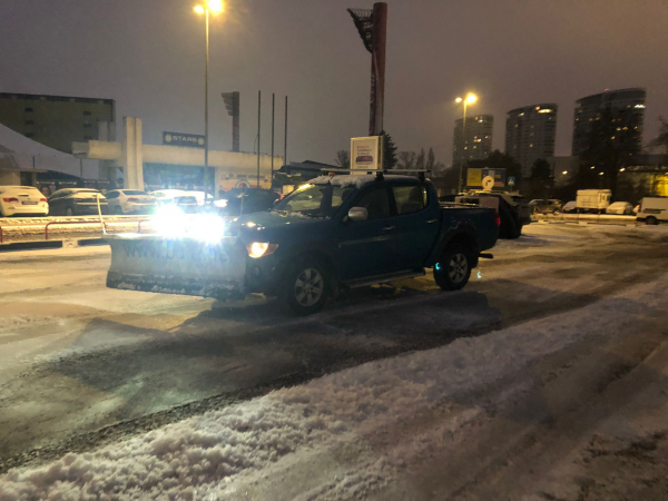 Vozidlo STONE TRADE vybavené radlicou a profesionálnym sypačom LEHNER POLARO 170 pri pluhovaní a posype parkovísk počas zimnej pohotovosti.