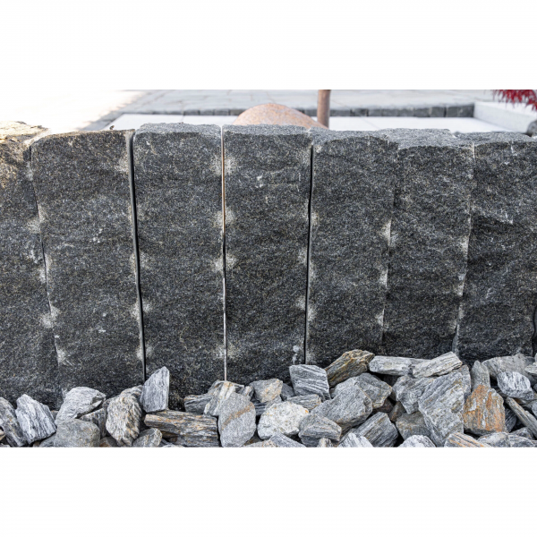 Tmavosivá žulová palisáda z línie Nero Z95 od StoneTrade použitá ako precízne olemovanie solitérneho kamenného kaktusu v okrasnej záhrade.