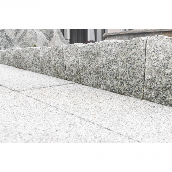 Detailné olemovanie a oddelenie svetlej a tmavej kamennej dlažby pomocou žulovej palisády Bianco Nero od STONE TRADE.