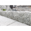 Detailné zobrazenie štiepaného povrchu žulovej palisády Bianco Nero od STONE TRADE použitej ako nízky okrasný obrubník pri svetlej dlažbe.