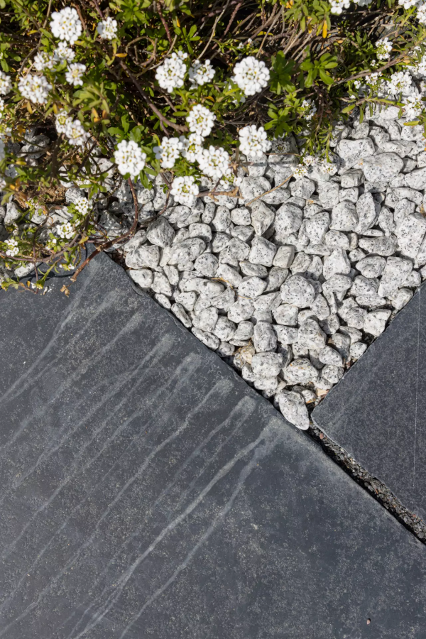 Detail dekoračných okruhliakov Žula Bianco Nero od STONE TRADE v záhradnej výsadbe