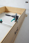 Detailný pohľad na upínacie čeľuste a fixačný mechanizmus montážnej rozpery Wolfcraft Pro pri osádzaní dvernej zárubne od stonetrade.